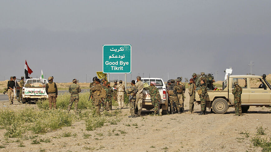 Shi'ite fighters gather with their weapons next to a sign in the town of al-Alam March 9, 2015. Just north of Tikrit, home city of executed Sunni former president Saddam Hussein, Iraqi security forces and Shi?ite militia fighters began an offensive against Islamic State to regain control over the town of al-Alam.   REUTERS/Thaier Al-Sudani (IRAQ - Tags: POLITICS CIVIL UNREST CONFLICT) - RTR4SOF4