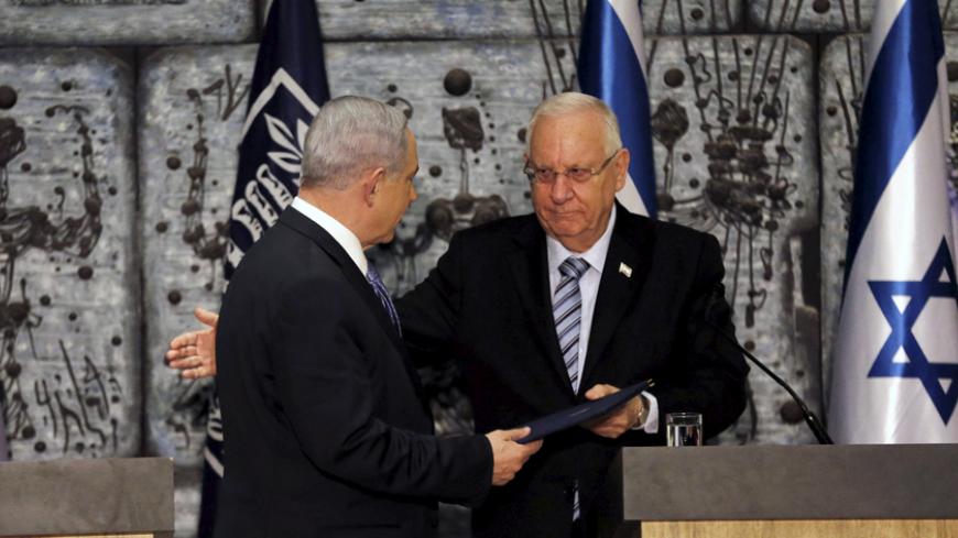 Israeli Prime Minister Benjamin Netanyahu (L) receives a folder from Israeli President Reuven Rivlin during a ceremony  in Jerusalem March 25, 2015. Netanyahu, grappling with fierce White House disapproval, won consent from Israel's president on Wednesday to try to form a new coalition government. REUTERS/Ammar Awad  - RTR4UVGJ