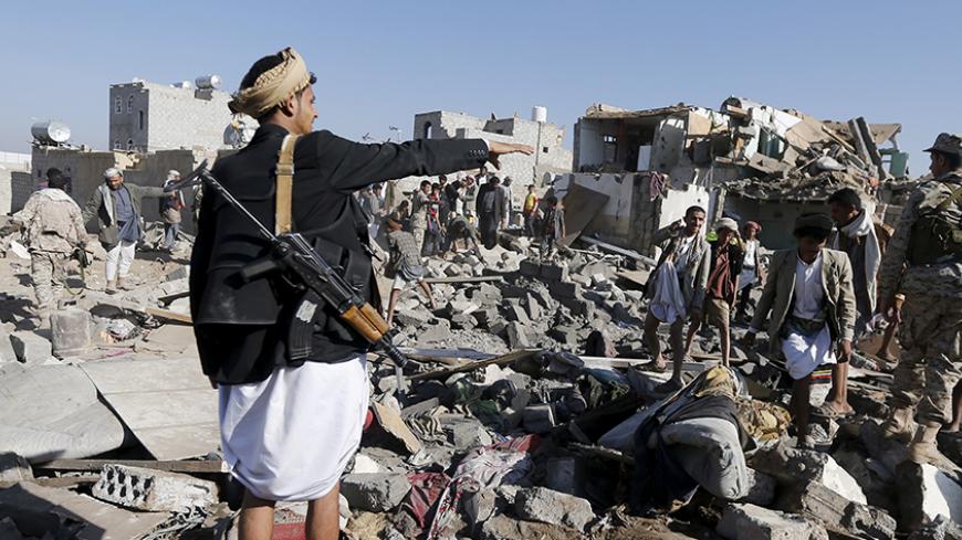 An armed man gestures as he stands on the rubble of houses destroyed by an air strike near Sanaa Airport March 26, 2015. Saudi Arabia and Gulf region allies launched military operations including air strikes in Yemen on Thursday, officials said, to counter Iran-allied forces besieging the southern city of Aden where the U.S.-backed Yemeni president had taken refuge.  REUTERS/Khaled Abdullah - RTR4UXIA