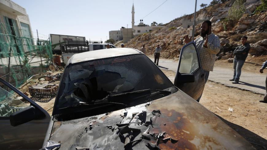 A Palestinian man gestures near a damaged car in the West Bank village of Burka, near Ramallah October 10, 2013. An Israeli police spokesperson said on Thursday three cars were damaged overnight and the words "Geulat Tzion loves Tomer Hazan" were scrawled in Hebrew on a wall of the mosque. Geulat Tzion is an illegal Jewish settler-outpost in the West Bank where structures were demolished by Israeli forces a day earlier and Tomer Hazan is an Israeli soldier who was killed by a Palestinian on September 21. RE