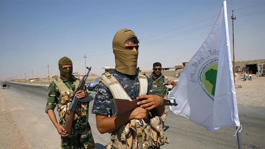 Fighters from the Shi'ite Badr Brigade militia stand near their flag as they guard at a checkpoint along a highway recently taken from militants of the Islamic State, outside the town of Sulaiman Pek September 5, 2014. The highway, which continues south to Baghdad, is now controlled by Shi'ite militia fighters and the Kurdish Peshmerga. REUTERS/Ahmed Jadallah (IRAQ - Tags: CIVIL UNREST POLITICS CONFLICT) - RTR454AO
