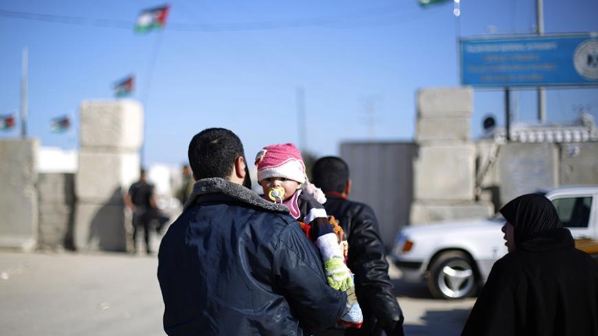 A Palestinian man holds a child near the Erez crossing in Beit Hanun in the north of the Gaza Strip on January 13, 2015. The head of the Palestinian authority for civil affairs, Hussein al-Sheikh, said that Hamas have taken over the Palestinian side of the Erez Crossing, while the Islamic movement which controls the impoverished Palestinian territory has accused the Palestinian authority of stopping work at the crossing "without justification." AFP PHOTO / MOHAMMED ABED        (Photo credit should read MOHA