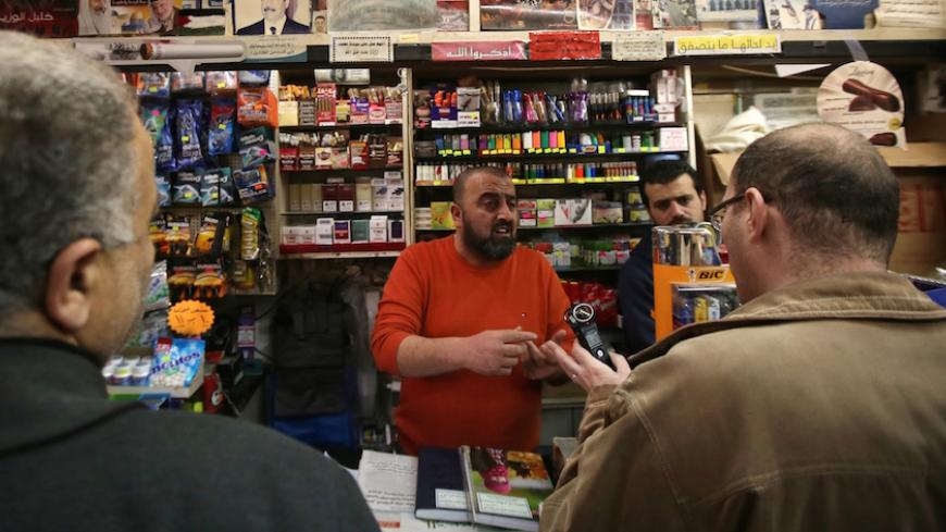 Supporters of the Palestinian Fatah movement talk with a shop keeper at a shop during a visit to convince retailers not to sell Israeli goods on February 24, 2015 in the West Bank city of Ramallah. A Palestinian commission launched a new campaign calling for the boycott of Israeli products in reaction to sanctions imposed by Israel following the recent Palestinian diplomatic offensive at the United Nations, the head of the commission told AFP.  AFP PHOTO / ABBAS MOMANI        (Photo credit should read ABBAS