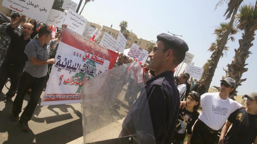 A Lebanese policeman stands guard, as Lebanese Shi'ites, who said they were forced to leave United Arab Emirates last year because of purported security reasons, hold banners during a protest to demand for their rights, in front of the UAE embassy in Beirut May 5, 2010.  REUTERS/Sharif Karim   (LEBANON - Tags: CIVIL UNREST POLITICS SOCIETY EMPLOYMENT BUSINESS) - RTR2DHH4