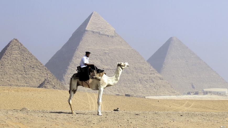 A security officer patrols the Giza Pyramids on his camel in Cairo, October 1, 2012. REUTERS/Mohamed Abd El Ghany  (EGYPT - Tags: ANIMALS TRAVEL SOCIETY) - RTR38NTP