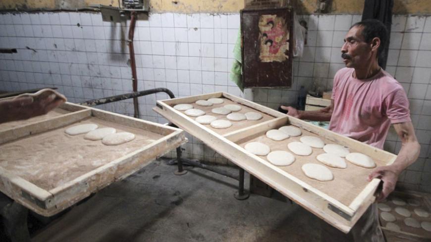 A baker works at a bakery shop in Cairo March 2, 2014. Egypt's new supplies minister Khaled Hanafi said he would reconsider a decision to halt rice exports and look into French wheat imports which were excluded after Egypt changed its specification concerning wheat moisture levels, state media reported on Sunday. REUTERS/Al Youm Al Saabi Newspaper (EGYPT - Tags: POLITICS BUSINESS COMMODITIES FOOD) - RTR3FWPK