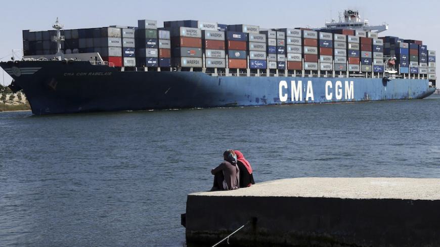 Women sit and look at a container ship navigate through the Suez canal near Ismailia port city, northeast of Cairo May 2, 2014. Egypt has extended the bidding deadline to July 3 in an international auction of 22 concessions for oil and gas exploration, an official with the state-owned gas company said on Wednesday.The previous deadline for companies to submit bids for concessions in the Suez Canal, Egypt's western desert, the Mediterranean sea and the Nile Delta had been May 19. REUTERS/Amr Abdallah Dalsh  