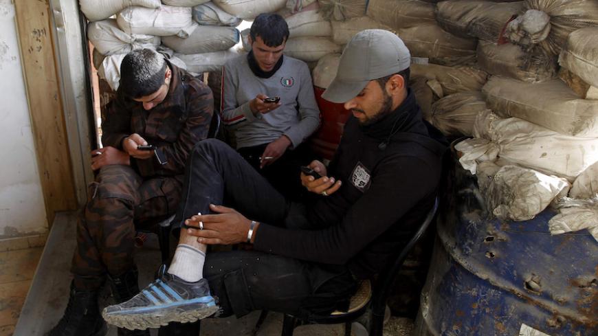 Free Syrian Army fighters use their smartphones behind sandbags in the Al-Maysar neighbourhood of Aleppo May 3, 2014. REUTERS/Jalal Al-Mamo (SYRIA - Tags: CIVIL UNREST MILITARY POLITICS SOCIETY CONFLICT) - RTR3NNM2