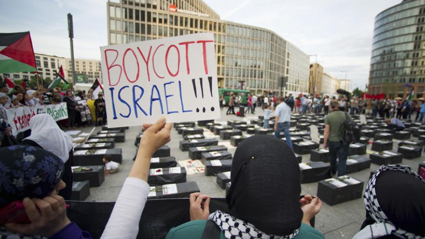 A woman holds a sign which reads "Boycott Israel" in front of symbolic coffins while attending a demonstration supporting Palestine, in Berlin August 1, 2014. Israel launched its Gaza offensive on July 8 in response to a surge of rocket attacks by Gaza's dominant Hamas Islamists. Hamas said that Palestinians would continue confronting Israel until its blockade on Gaza was lifted. REUTERS/Steffi Loos (GERMANY - Tags: POLITICS CIVIL UNREST) - RTR40YJG