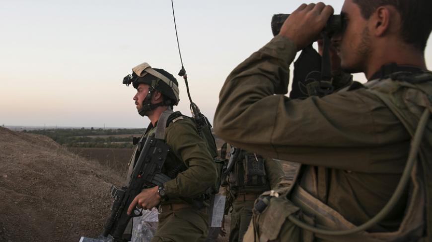 An Israeli soldier looks through binoculars at an observation post overlooking the Gaza strip near the Israeli-Gaza border August 20, 2014. An Israeli air strike in Gaza killed the wife and infant son of Hamas's military leader, Mohammed Deif, the group said, calling it an attempt to assassinate him after a ceasefire collapsed. Palestinians launched more than 100 rockets, mainly at southern Israel, with some intercepted by the Iron Dome anti-missile system, the military said. No casualties were reported on 