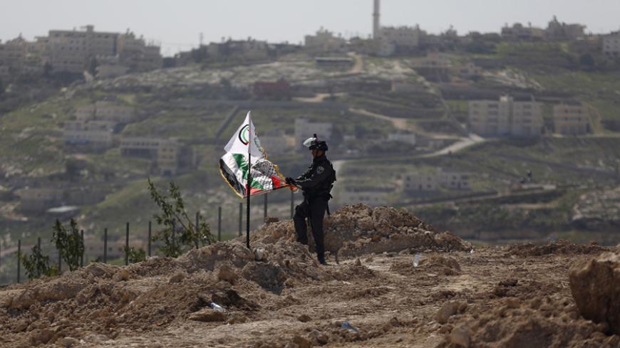 An Israeli border policeman removes a Palestinian flag and a Fatah flag during a protest against what Palestinians say is land confiscations by Israel for Jewish settlements, near the West Bank town of Abu Dis near Jerusalem March 6, 2015. REUTERS/Mohamad Torokman (WEST BANK - Tags: POLITICS CIVIL UNREST) - RTR4SCB7