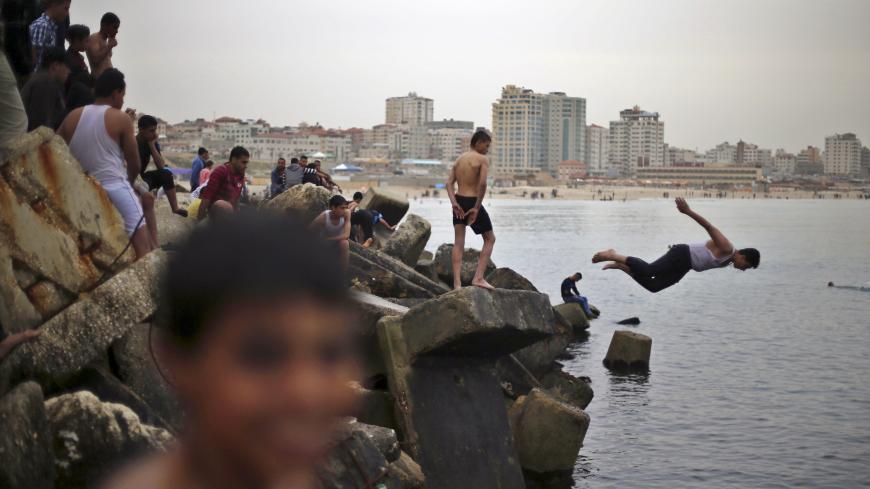 A Palestinian boy jumps into the Mediterranean Sea as he enjoys a warm day with others at the seaport of Gaza City March 27, 2015. REUTERS/Mohammed Salem 







