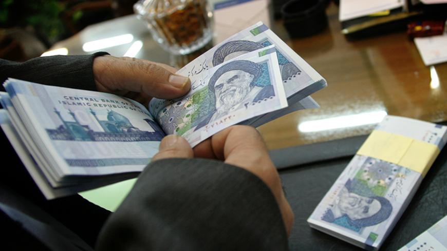 An Iranian bank teller counts new 20,000 rial notes at Iran's Central Bank in Tehran March 15, 2004. Iran began to release the new 20,000 rial note equivalent to $2.38 shortly before the Iranian new year which begins March 21. REUTERS/Morteza Nikoubazl  CJF/AA - RTRF83M