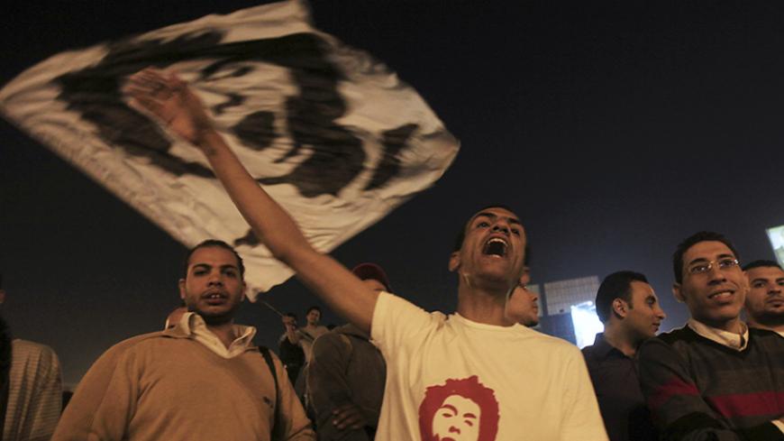 Demonstrators wave a flag with a picture of youth activist Gaber Salah on a defaced monument, in the centre of Tahrir Square as protesters against Egypt's Army Chief General Abdel Fattah al-Sisi and those against the Muslim Brotherhood hold rallies, in Cairo November 18, 2013. The government says the monument honours the "martyrs" not only of the 2011 anti-Mubarak uprising, but also of what it calls the "June 30 revolution," referring to the date of the mass disturbances that precipitated Mursi's ouster; bu