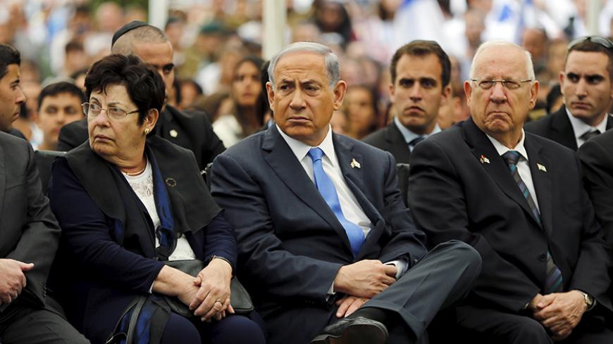 Israel's Prime Minister Benjamin Netanyahu (C) sits next to President Reuven Rivlin (R) during a Memorial Day ceremony at Mount Herzl military cemetery in Jerusalem April 22, 2015. Israel on Wednesday marks Memorial Day to commemorate its fallen soldiers. REUTERS/Ammar Awad  - RTX19SR0