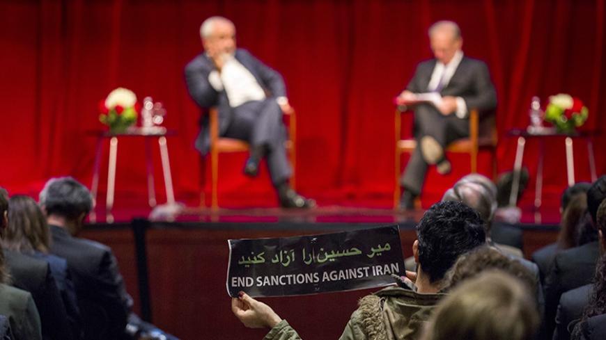 A demonstrator holds up a sign while Iranian Foreign Minister Mohammad Javad Zarif speaks with Washington Post journalist David Ignatius at the New York University (NYU) Center on International Cooperation in New York April 29, 2015. Iran's foreign minister on Wednesday offered assurances that Tehran is committed to maintaining freedom of navigation in the Persian Gulf in the aftermath of the seizure of a commercial ship by Iranian forces a day earlier. REUTERS/Lucas Jackson  - RTX1AUZQ