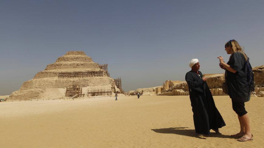 A guide speaks to a tourist near the Djoser's step pyramid in Saqqara, outside of Cairo March 5, 2011. Sites around the great pyramid at Giza, a Wonder of the Ancient World, the Sphinx and the cemetery at Sakkara have been nearly empty of tourists since a revolt started a month ago that ousted Hosni Mubarak and now Egypt wants visitors to return. REUTERS/Peter Andrews (EGYPT - Tags: CIVIL UNREST POLITICS TRAVEL SOCIETY) - RTR2JGZU