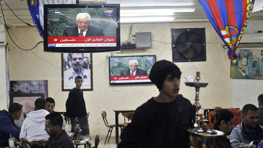 Palestinians sit in a cafe, as Palestinian President Mahmoud Abbas is seen on a television, in the West Bank city of Ramallah November 29, 2012. The 193-nation U.N. General Assembly overwhelmingly approved a resolution on Thursday to upgrade the Palestinian Authority's observer status at the United Nations from "entity" to "non-member state," implicitly recognizing a Palestinian state. REUTERS/ Mohamad Torokman (WEST BANK - Tags: POLITICS) - RTR3B1FV