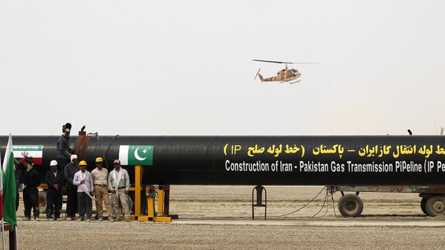 Irani workers stand near as a security helicopter lands near the pipeline during a groundbreaking ceremony to mark the inauguration of the Iran-Pakistan gas pipeline, in the city of Chahbahar in southeastern Iran March 11, 2013. Ahmadinejad and Zardari marked the start of Pakistani construction on the much-delayed gas pipeline on Monday, Iranian media reported, despite U.S. pressure on Islamabad to back out of the project. REUTERS/Mian Khursheed    (IRAN - Tags: POLITICS ENERGY) - RTR3EUW9