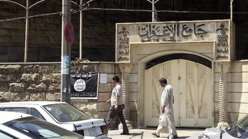 People walk past a banner (in black and white) belonging to the Islamic State in Iraq and the Levant (ISIL) in the city of Mosul, June 28, 2014. Since early June, ISIL militants have overrun most majority Sunni Muslim areas in the north and west of Iraq, capturing the biggest northern city Mosul and late dictator Saddam Hussein's hometown of Tikrit. The banner reads, "There is no God but God, and Mohammad is his messenger."  REUTERS/Stringer (IRAQ - Tags: CIVIL UNREST POLITICS) - RTR3W71S