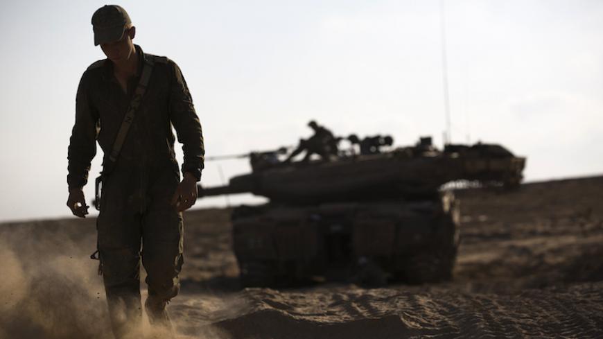 An Israeli soldier walks near his tank just outside the Israeli border with the northern Gaza Strip August 23, 2014. Egypt called on Israel and the Palestinians on Saturday to halt fire and resume peace talks, but violence continued unabated with Israeli air strikes in the Gaza Strip and Hamas militants firing rockets at the Jewish state.    REUTERS/Amir Cohen (ISRAEL - Tags: POLITICS CIVIL UNREST MILITARY CONFLICT) - RTR43H0K