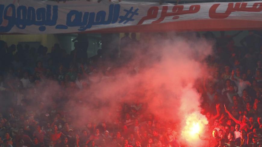 Egyptian soccer fans known as "Ultras" shout slogans against the government and police while holding a flare during the African Nations Cup qualifying soccer match between Egypt and Botswana, in Cairo October 15, 2014. The banner reads, "Ultras not a criminal, Freedom for fans".REUTERS/Amr Abdallah Dalsh  (EGYPT - Tags: SPORT SOCCER CIVIL UNREST) - RTR4ACF9