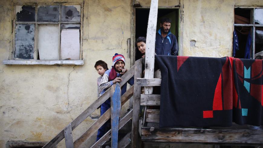 A Syrian refugee family is seen in front of their house in Ankara November 21, 2014. Syrian refugees across the Middle East, some in exile for a fourth winter, face freezing temperatures, hunger and increasing hostility from locals as governments struggle to cope with the humanitarian crisis. Lebanon and Jordan are tightening their borders to stem the flow of those trying to escape whilst in Turkey, widely praised for hosting around half Syria's estimated 3.2 million refugees, the influx threatens to upset 