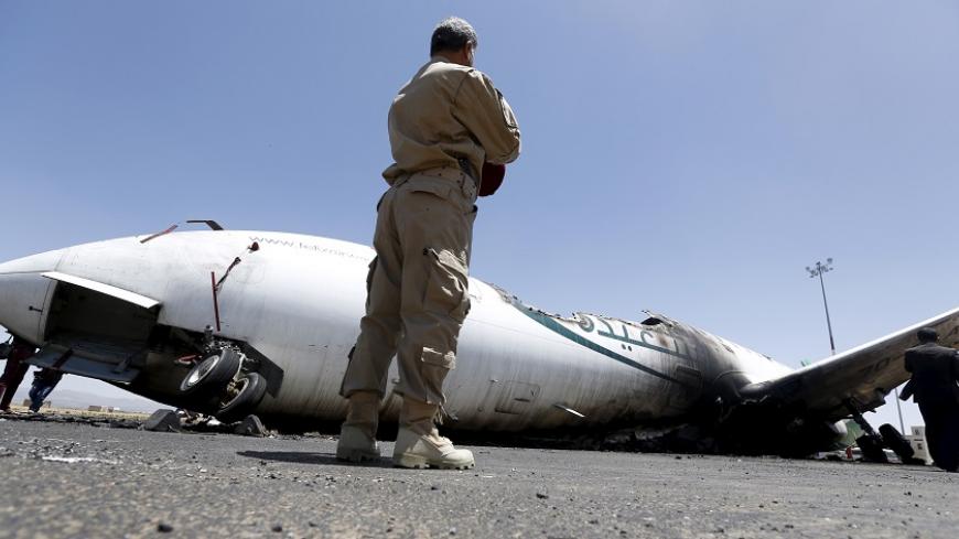 An army officer looks at a Felix Airways plane, destroyed by an air strike at the international airport of Yemen's capital Sanaa, April 29, 2015. Jets from a Saudi-led alliance destroyed the runway of Yemen's Sanaa airport on Tuesday to prevent an Iranian plane from landing there, Saudi Arabia said, as fighting across the country killed at least 30 people. Airport officials said the strikes set a civilian aircraft operated by Yemeni Felix Airways ablaze. REUTERS/Khaled Abdullah