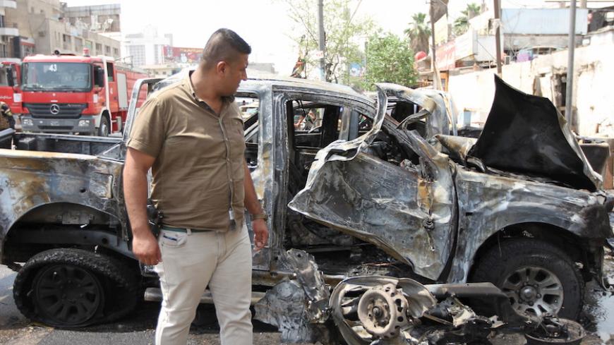A member of the Iraq security forces looks at the site of a car bomb attack in Baghdad May 9, 2015.  The attack killed seven civilians and wounded 14 others, police and medical sources said. REUTERS/Stringer - RTX1C8E9