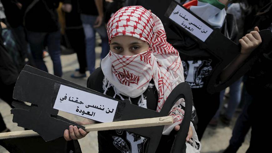 A Palestinian girl holds a cut-out of a key during a rally ahead of the Nakba day in the West Bank city of Bethlehem May 14, 2015. Palestinians mark "Nakba" (Catastrophe) on May 15 to commemorate the expulsion or fleeing of some 700,000 Palestinians from their homes in the war that led to the founding of Israel in 1948. The Arabic writing reads, "we will not forget our right of return." REUTERS/Ammar Awad - RTX1CYI7