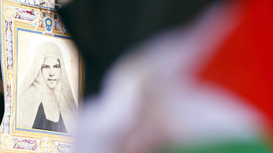 A Palestinian flag waves in front of a tapestry of Mariam Baouardy Haddad before Pope Francis leads a ceremony for the canonisation of four nuns at Saint Peter's square in the Vatican City, May 17, 2015.  The four nuns being canonised include two Palestininan nuns, Marie Alphonsine Ghattas, founder of the first Catholic congregation in Palestine, and Mariam Baouardy Haddad, who established a Carmelite convent in Bethlehem.      REUTERS/Tony Gentile - RTX1DB51
