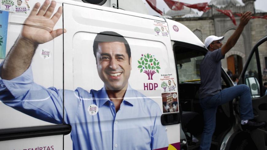 A supporter of pro-Kurdish People's Democratic Party (HDP) stands on an election campaign minibus with a picture of the party's co-chair Selahattin Demirtas on it, in Istanbul, Turkey, May 28, 2015. Turkey's Pro-Kurdish People's Democratic Party (HDP) said on Wednesday June elections would lack legitimacy if a threshold for parliamentary representation deprived it of representation, but it would remain a partner in peace talks with militants. The fate of the HDP, which hopes to cross the 10 percent national