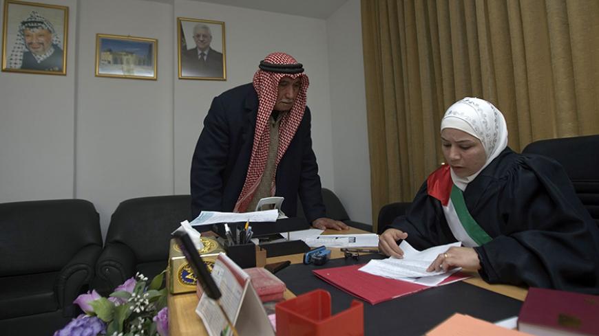 Newly appointed Palestinian judge Khouloud Al-Faqih (R) looks at documents in her office in the West Bank city of Ramallah February 23, 2009. Palestinian President Mahmoud Abbas ordered last week the appointment of the first two female judges in the Palestinian Authority, one of them Al-Faqih. Picture taken February 23, 2009.
REUTERS/Fadi Arouri (WEST BANK) - RTXC0RR