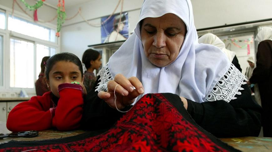 A Palestinian woman is watched by a young girl as she embroiders in a women programme center in Gaza City January 5, 2003, where women are taught hairdressing, stitching and embroidery and IT skills. [Palestinian women have been exposed to increased domestic violence since the beginning of the intifada, or Palestinian uprising, 29 months ago, according to the Palestinian Center for Public Opinion (PCPO), which was commissioned by a Palestinian women's organization to conduct a poll. The poll showed that 86 