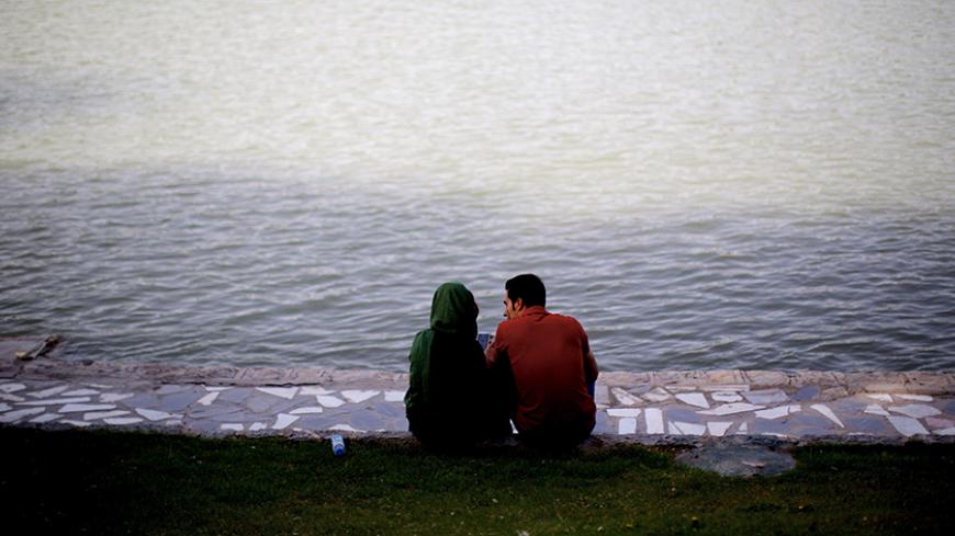 An Iranian couple sit on the bank of Zayandeh roud river, which was completely dry in recent years, in the historic city of Isfahan some 400 kms south of the capital, Tehran, on April 21, 2015. AFP PHOTO/BEHROUZ MEHRI        (Photo credit should read BEHROUZ MEHRI/AFP/Getty Images)