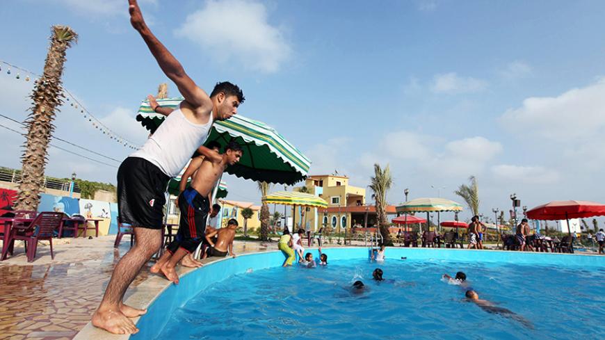 Palestinians jump into a pool at Crazy Water Park in Gaza City August 3, 2010. New leisure projects and restaurants have been springing up in the Gaza Strip, some partially funded by Hamas Islamists ruling a territory long seen as a symbol of Palestinian hardship. REUTERS/Mohammed Salem (GAZA - Tags: BUSINESS ENVIRONMENT SOCIETY RELIGION TRAVEL) - RTR2H0CZ