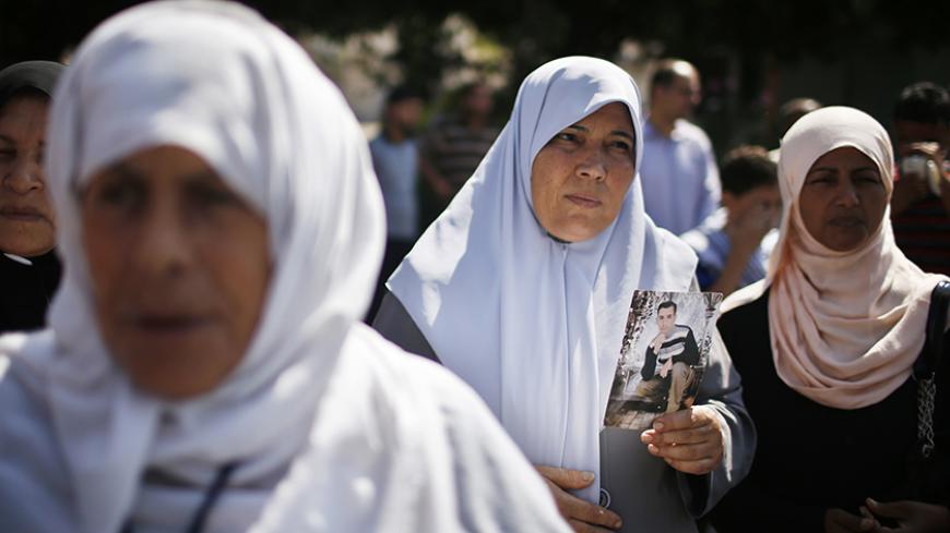 A Palestinian woman holds a picture of a jailed relative during a rally in solidarity with hunger-striking Palestinian prisoners held by Israel, in Gaza City June 11, 2014. Israel's parliament has given initial approval to a law to enable the force-feeding of Palestinian prisoners on a hunger strike, drawing defiance from activists who said on Tuesday it would not deter the inmates.  REUTERS/Mohammed Salem (GAZA - Tags: POLITICS) - RTR3T6PC