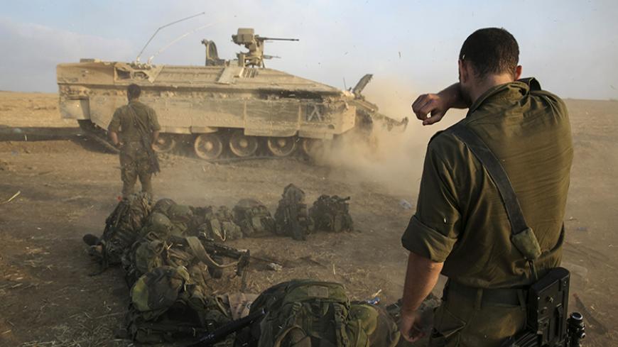 An Israeli soldier stands at a staging area after crossing back into Israel from Gaza July 28, 2014. Israel eased its assaults in the Gaza Strip and Palestinian rocket fire from the enclave declined sharply on Monday, the military said, with both the United States and United Nations calling for a durable ceasefire. REUTERS/Baz Ratner (ISRAEL - Tags: CIVIL UNREST CONFLICT MILITARY POLITICS) - RTR40CN3