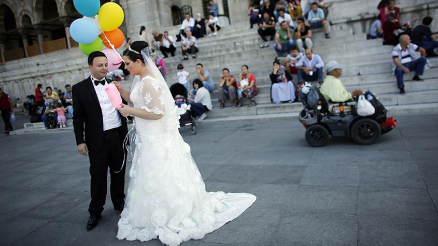 Bride Mutlu and groom Ihsan Baran pose for their photographer in front of the New mosque at Eminonu square in Istanbul September 11, 2014. REUTERS/Murad Sezer (TURKEY - Tags: SOCIETY) - RTR45W6X