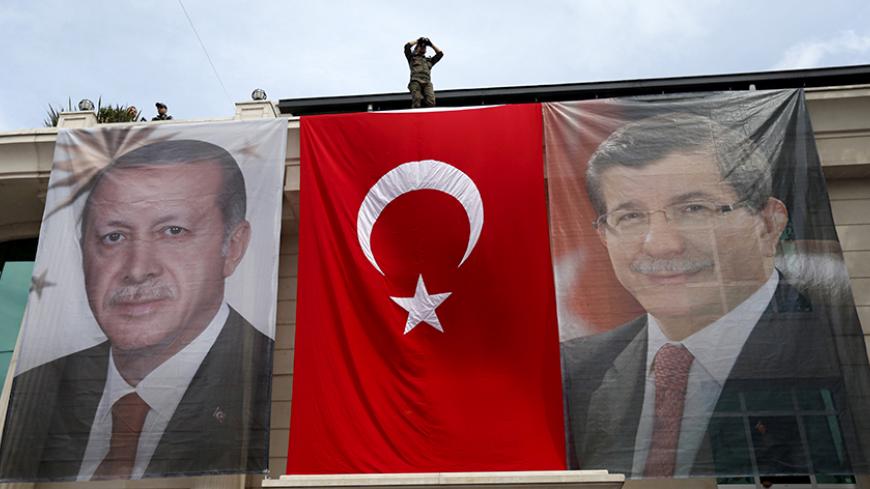 A special forces police officer takes security measures as he stands on top of a building where the portraits of Turkey's President Tayyip Erdogan (L), Prime Minister Ahmet Davutoglu and a Turkish flag are displayed in Istanbul, Turkey, June 3, 2015. Turkey holds a parliamentary election on June 7 that could reshape its political landscape. Erdogan hopes the result will help move Turkey towards a presidential system, while the pro-Kurdish opposition is aiming to enter parliament as a party for the first tim