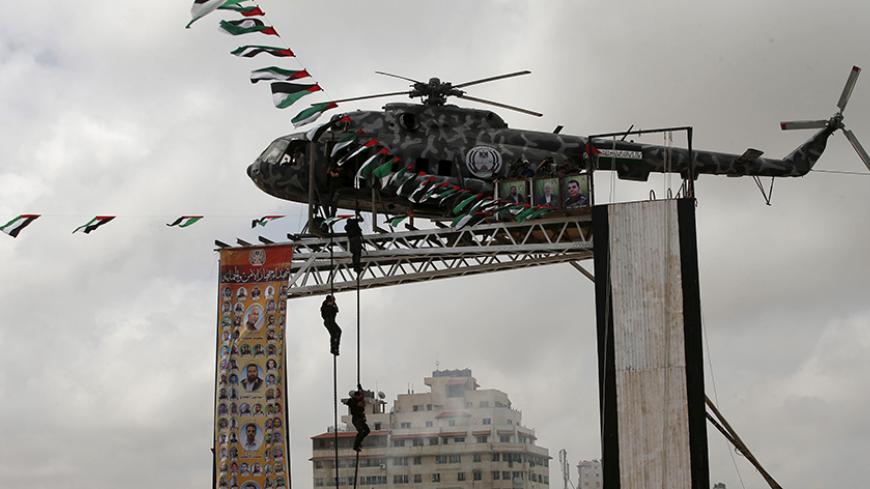 Members of Palestinian security forces loyal to Hamas rappel down the broken helicopter of late Palestinian President Yasser Arafat which was placed on top of a structure during a military graduation ceremony in Gaza City May 21, 2015. REUTERS/Suhaib Salem



 - RTX1DWZ2