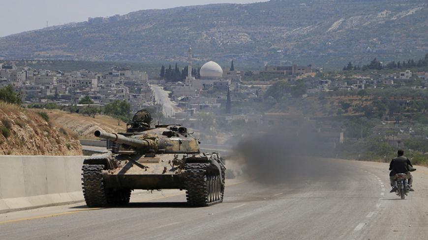 Jund al-Aqsa fighters part of a coalition of rebel groups called Jaish al Fateh (Conquest Army), drive in a tank on a highway which connects Damascus to Aleppo, near Psoncol town after saying they had taken control of it, in the Idlib countryside, Syria June 6, 2015. REUTERS/Mohamad Bayoush - RTX1FDZA