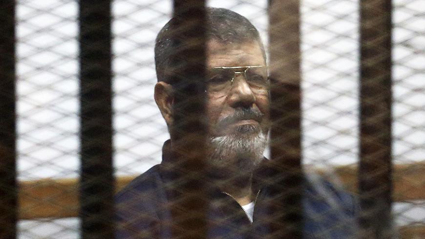 Deposed Egyptian President Mohamed Mursi listens to his verdict behind bars at a court on the outskirts of Cairo, Egypt June 16, 2015. An Egyptian court sentenced Mursi to death on Tuesday on charges of killing, kidnapping and other offences during a 2011 mass jail break.The general guide of the Muslim Brotherhood, Mohamed Badie, and four other Brotherhood leaders were also handed the death penalty. More than 80 others were sentenced to death in absentia. REUTERS/Asmaa Waguih - RTX1GQKQ