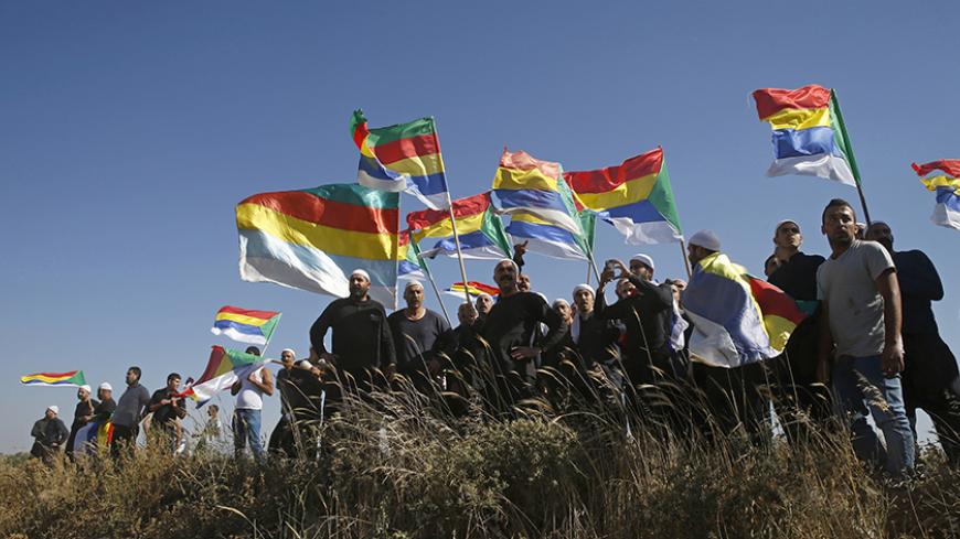 Members of the Druze community watch the fighting in the Druze village of Khadr in Syria, as they stand on the Israeli side of the border fence between Syria and the Israeli-occupied Golan Heights, near Majdal Shams, June 16, 2015. Israel's president expressed his concern to the United States last week about the fate of the Druze minority in Syria, saying around 500,000 of them were under threat from Islamist militants in an area near the Israeli border. REUTERS/Baz Ratner  - RTX1GRM4