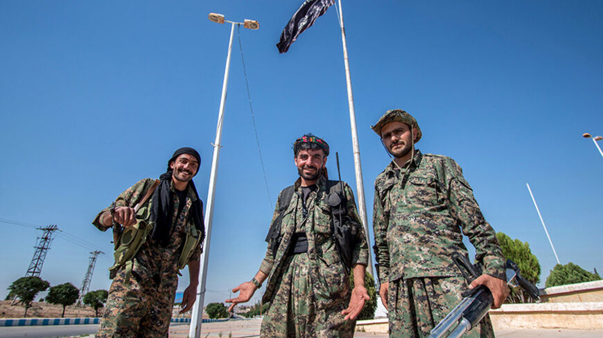 Kurdish People's Protection Units (YPG) fighters stand near an Islamic State flag in Tel Abyad town, Raqqa governorate, June 16, 2015. With a string of victories over Islamic State, Syria's Kurds are proving themselves an ever more dependable ally in the U.S.-led fight against the jihadists and building influence that will make them a force in Middle Eastern politics. Aided by U.S.-led air strikes, the Kurdish-led YPG militia may have dealt Islamic State its worst defeat to date in Syria by seizing the town