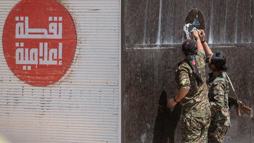 Kurdish People's Protection Units (YPG) fighters remove an Islamic State sticker in Tel Abyad town, Raqqa governorate, June 16, 2015. With a string of victories over Islamic State, Syria's Kurds are proving themselves an ever more dependable ally in the U.S.-led fight against the jihadists and building influence that will make them a force in Middle Eastern politics. Aided by U.S.-led air strikes, the Kurdish-led YPG militia may have dealt Islamic State its worst defeat to date in Syria by seizing the town 