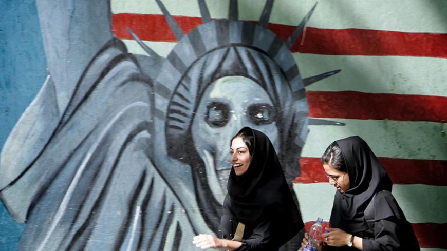 Iranian women walk past a satirical mural of the Statue of Liberty on the wall of former U.S. embassy in Tehran, Iran April 16, 2006. REUTERS/Morteza Nikoubazl - RTR1CJLR