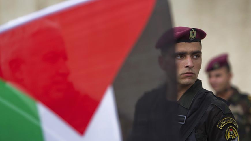 A member of the Palestinian security forces is seen behind a flag during a celebration in the West Bank city of Ramallah upon the return of Palestinian President Mahmoud Abbas from the U.N. General Assembly in the U.S., September 25, 2011. The Palestinians want the United Nations Security Council to decide on their bid for full membership of the world body within a fortnight, a leading official in the Fatah movement of President Mahmoud Abbas said on Saturday. REUTERS/Darren Whiteside (WEST BANK - Tags: POL