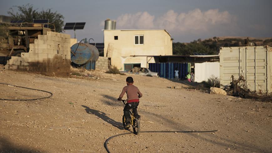 A Bedouin boy rides his bike through the 'unrecognised' village of Um Al-Hiram in southern Israel's Negev desert, October 16, 2014. For decades Arab Bedouins have eked out a meagre existence in the Negev desert, living without mains water, electricity or sanitation, and largely under the government's radar, but now Israel wants to move some 40,000 Bedouins from more than 30 'unrecognised' villages into government-built townships. Legislation underpinning the proposed mass uprooting was put on hold late last