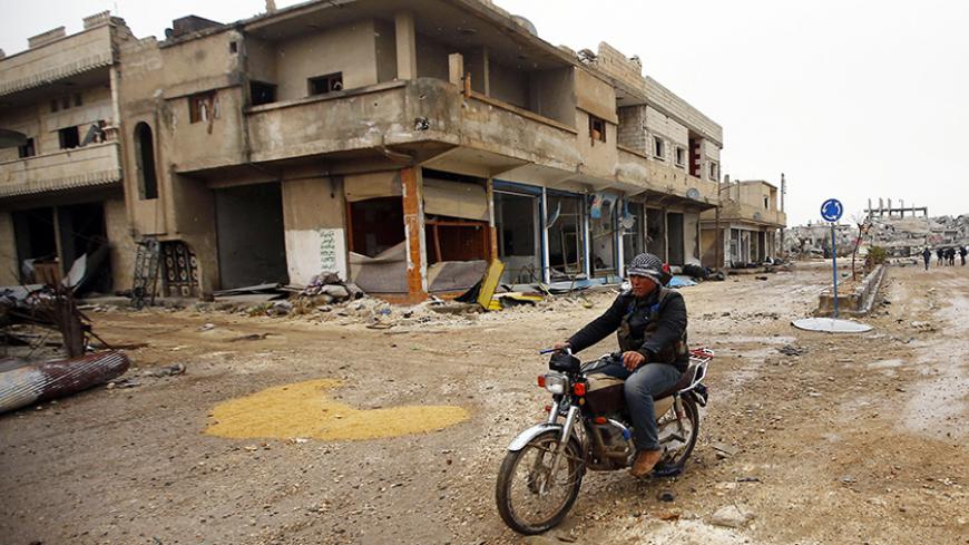 A fighter of the Kurdish People's Protection Units (YPG) patrols on a motorcycle in the streets of the northern Syrian town of Kobani January 30, 2015. Sheets meant to hide residents from snipers' sights still hang over streets in the Syrian border town of Kobani, and its shattered buildings and cratered roads suggest those who fled are unlikely to return soon. Kurdish forces said this week they had taken full control of Kobani, a mainly Kurdish town near the Turkish border, after months of bombardment by I